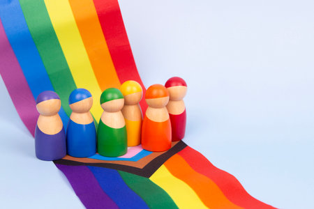 LGBT pride month background. Small wooden figurines of people standing on LGBTQ rainbow flag. Diversity and inclusivity conceptの写真素材