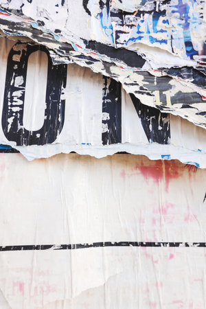 Old billboard with ripped posters. White torn posters texture background in city street