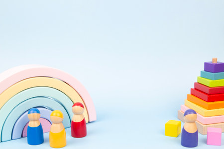 Colorful wooden toys including a rainbow and stacking blocks. Three diverse children figures are...