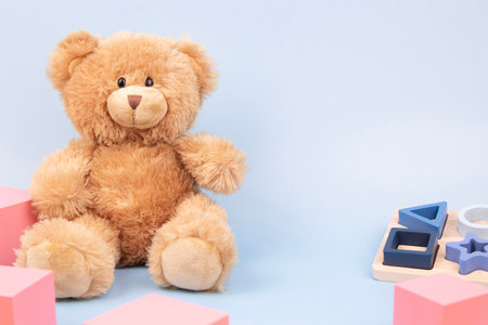 Kid toys background. Teddy bear, stacking sorting sensorial toys and pink cubes on blue background....