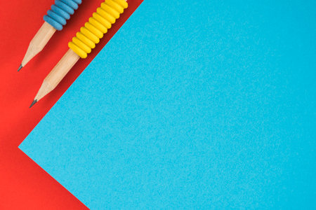 Geometric background with red and blue colors paper layout and two pencils. Top viewの写真素材