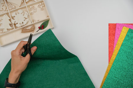 Handmade Christmas and New Years Home Decor. Woman hand making felt Xmas tree. Top view of Christmas DIY crafts and home decor supplies on tableの写真素材