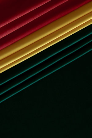 Black History Month, Juneteenth background. Red, yellow, green colors drapery, silk flag on black satin background. Top viewの写真素材