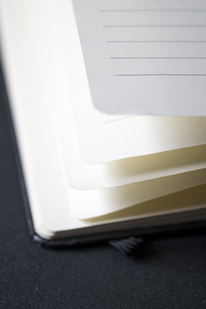 Opened business notepad with white sheets on the black desk