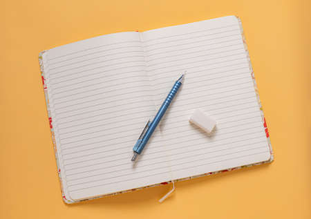 An open notebook with a pencil and eraser To convey ideas on a blank page. on a yellow backgroundの写真素材