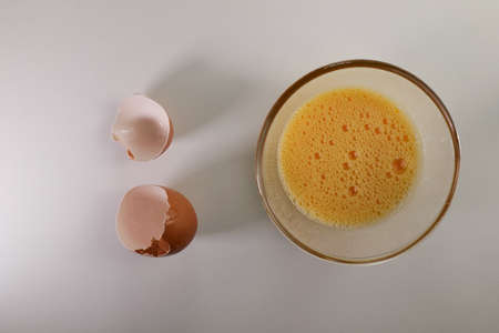 Crack the eggs into a small bowl and use a fork to beat the yolks and whites together and ready to cook other dishes.の写真素材