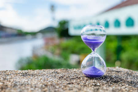 The hourglass stood on the rough rock surface near the rising tide canal. It shows that the flowing water never flows back. time tooの写真素材
