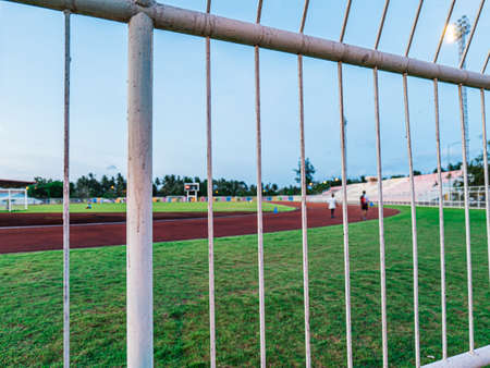 The fenced off stadium where people are exercising is jogging, walking, kicking football and so on, there's plenty of activity to do.の素材 [FY310178558718]