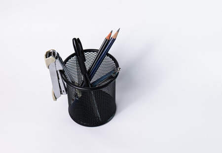 A small black basket made of round steel. Can be used to store office supplies, including pens, pencils, stapler, and still have space to put more things. In the white background there is copy space.の写真素材