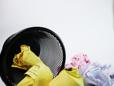 A small black basket made of round iron fell down. It is used to put the trash, documents that are not working and are overflowing to the outside. In the white background there is a copy space.の写真素材