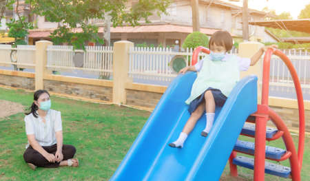 Parents take students to family activities. Play on the playground equipment, slides, slide down, two people, evening after school.の写真素材