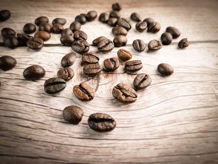 Close up shot of coffee beans was poured on the wooden floor focus at some point Gives a warm light to a warm mood insert a little darkness shooting in the studioの写真素材