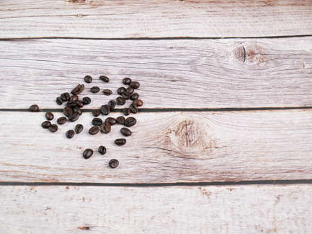 Close up shot of coffee beans was poured on the wooden floor focus at some point provide bright tones leave a gap on the side shooting in the studioの写真素材