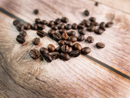 Close up shot of coffee beans was poured on the wooden floor focus at some point Gives a warm light to a warm mood insert a little darkness shooting in the studioの写真素材