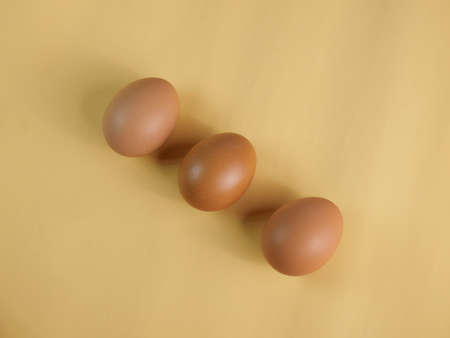 Lay three eggs in a row, arranged diagonally. Shot in a studio with light and shadows against an eggshell colored background.の写真素材