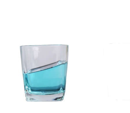 glass for liquor put blue liquid made of glass resting on a tilted table white backgroundの写真素材