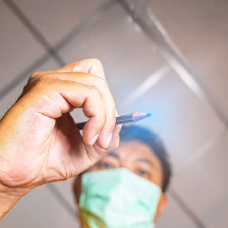 Capture the angle of the pencil writing. There is a blurry and sharp image of a person wearing a...