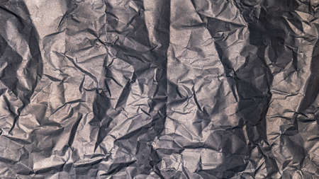 The black paper background is wrinkled, creating a rough texture with light and shadow.の写真素材