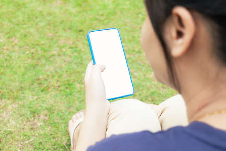 Taken from behind, across the shoulder of a blurry Asian woman. But clearly the mobile phone that...