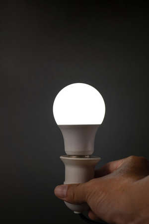 mobile led bulb that illuminates a white light on a black background in the dark