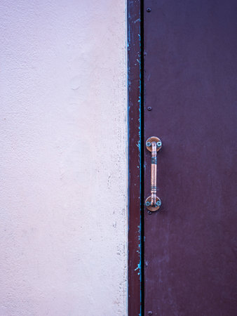 Rough cement wall surfaces painted in pastel orange two tones and steel doors with door handles.の写真素材