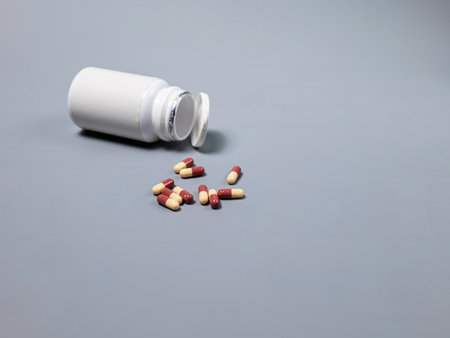 Pills spilling out of pill bottle white and two-colored capsules pills  Medicines and prescription pills flat lay background. White medical pills and tablets spilling out of a drug bottle.Copy space for textの写真素材