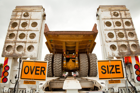 An over-sized yellow mining dump truck on a float trailer ready for transportation. Wide load.の写真素材