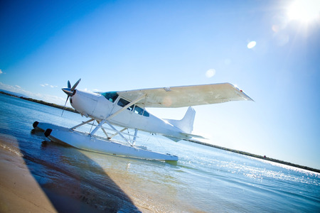Sea float plane approaching beach with rich blue sky and sun backgroundの写真素材