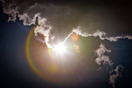 The sun shining brightly behind Cloudsの写真素材