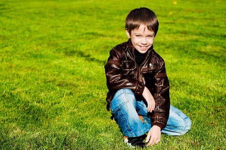 Little 7 year boy Lying Down on the green grass and smilingの写真素材