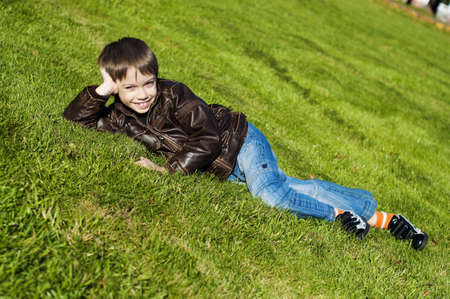 Little 7 year boy Lying Down on the green grass and smilingの写真素材