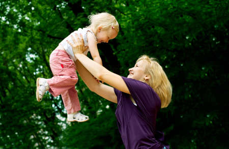 mother embrace her young daughter in the green cityparkの写真素材