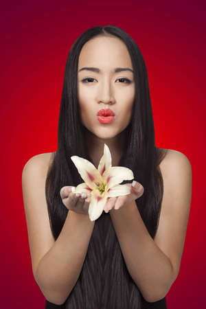 chinese girl is holding lily in her hands on the red backgroundの写真素材