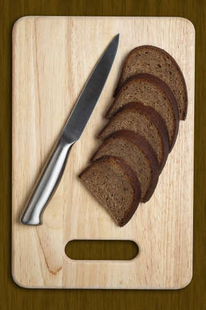 metallic knife and sliced bread on the kitchen boardの写真素材
