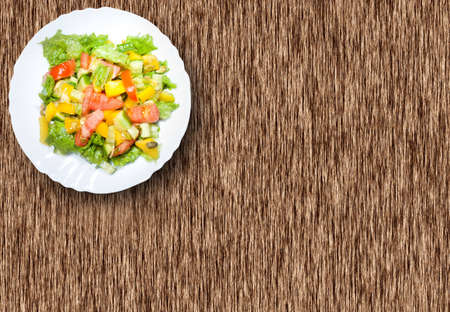 Salad with tomato, pepper, pumpkin seeds on the white  plate on the wood tableの写真素材