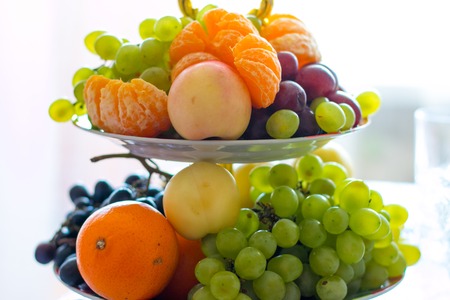Vase with fruits. Oranges, green grapes applesの写真素材