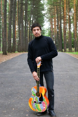 Man in the park with a guitar in his hands. Hippie style.の写真素材