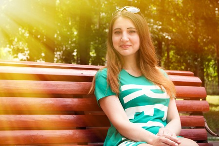 Beautiful model sits on a bench in the Park. Summerの写真素材