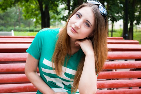 Beautiful model sits on a bench in the Park. Summerの写真素材