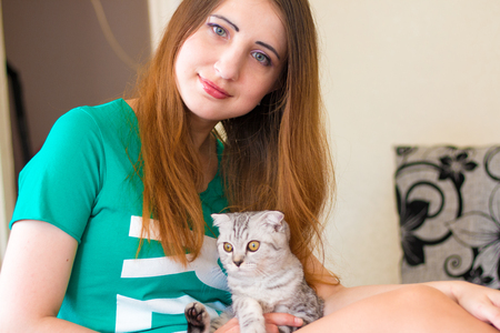 Baby cat laying on woman legs. Gray kitten, a favorite of the beautiful hostess. Morningの写真素材