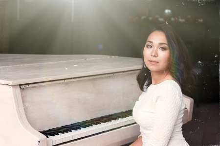sexy brunette with very long hair sitting at the piano. Sun shootの写真素材