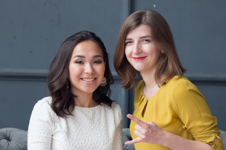 front view of two smiling young female friends sitting in the living room at home. 2016の写真素材