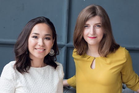 front view of two smiling young female friends sitting in the living room at home. 2016の写真素材