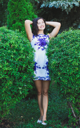 Sexy young girl between two large bushes in a short dress.の写真素材