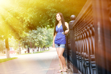 The Sun's rays fall on the girl leaned on the fence.の写真素材