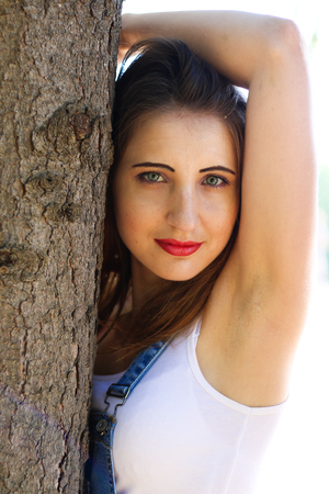 Woman in overalls stands between tree trunksの写真素材