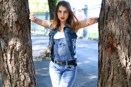 Woman in overalls stands between tree trunksの写真素材