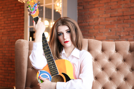Girl in white shirt posing with a guitar in hippie styleの写真素材