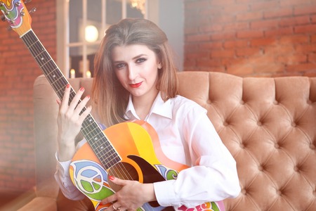 Girl in white shirt posing with a guitar in hippie styleの写真素材