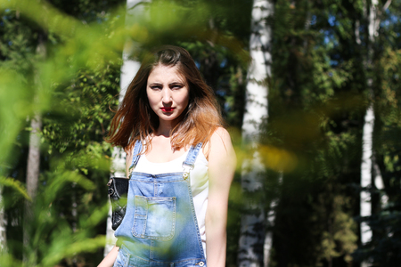 Young woman posing on the background, the foreground bushesの写真素材